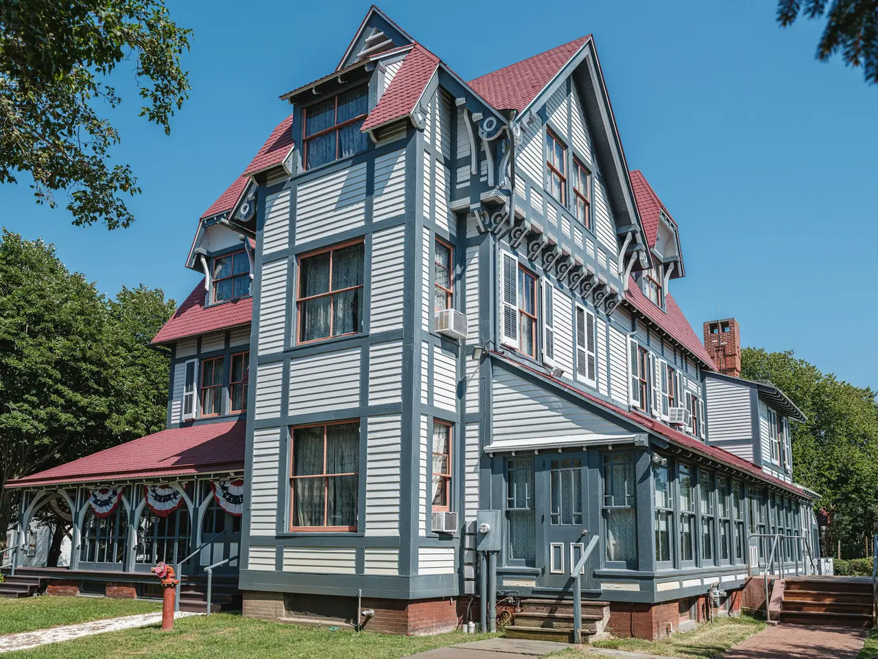 A grey and red Victorian house in Cape May, New Jersey, on a sunny day.