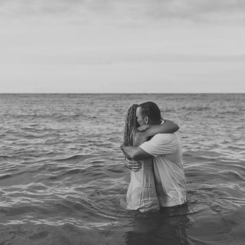 Heather and Jim McNulty embracing, waist-deep in the ocean, in a black-and-white photo.